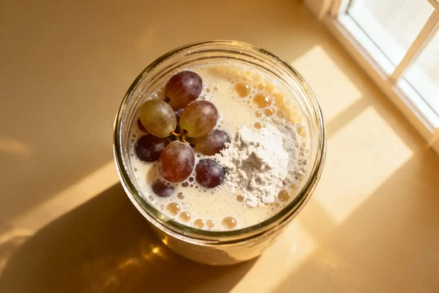 Levure de boulanger maison en préparation avec raisins et farine dans un bocal en verre, bulles visibles